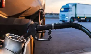 Pistolet dystrybutora paliwa wlewa się do baku ciężarówki TIR na stacji paliw.