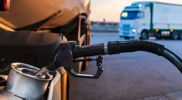 Pistolet dystrybutora paliwa wlewa się do baku ciężarówki TIR na stacji paliw.