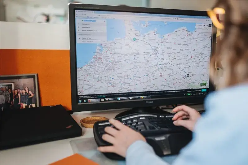 Spedytor przy komputerze z mapą i telefonem